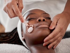 facial-roller-spa-black-woman-relax-massage-wellness-skincare-cosmetics-salon-beauty-face-beautician-with-rose-tool-healthy-dermatology-crystal-stone-aesthetic-glow